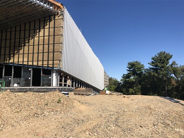 Installation of the standing metal seam system. Shown in photo at various stages is the insulation, framing and siding on the East side of the building.