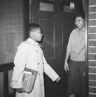 Ronald Deskins, 12, exchanges smiles with his mother, Mrs. Carroll A. Deskins, as he leaves his home in Arlington, Va., on Feb. 2, 1959 to be one of the first African-American children to attend classes in a formerly all-white Virginia public school Stratford Junior High. He joined three other African-American children in entering the rear of the heavily guarded school without disturbance. (AP Photo)