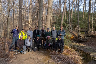 Group photo, 13 volunteers and County staff with stream in background