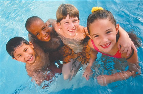 Four children in a pool with arms around each other