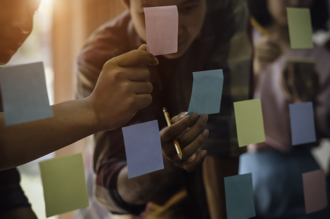 hands sticking sticky notes on window