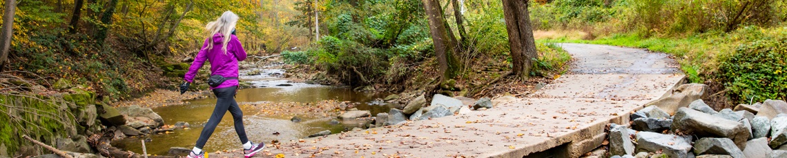 lady walking on trail with fall foliage in background