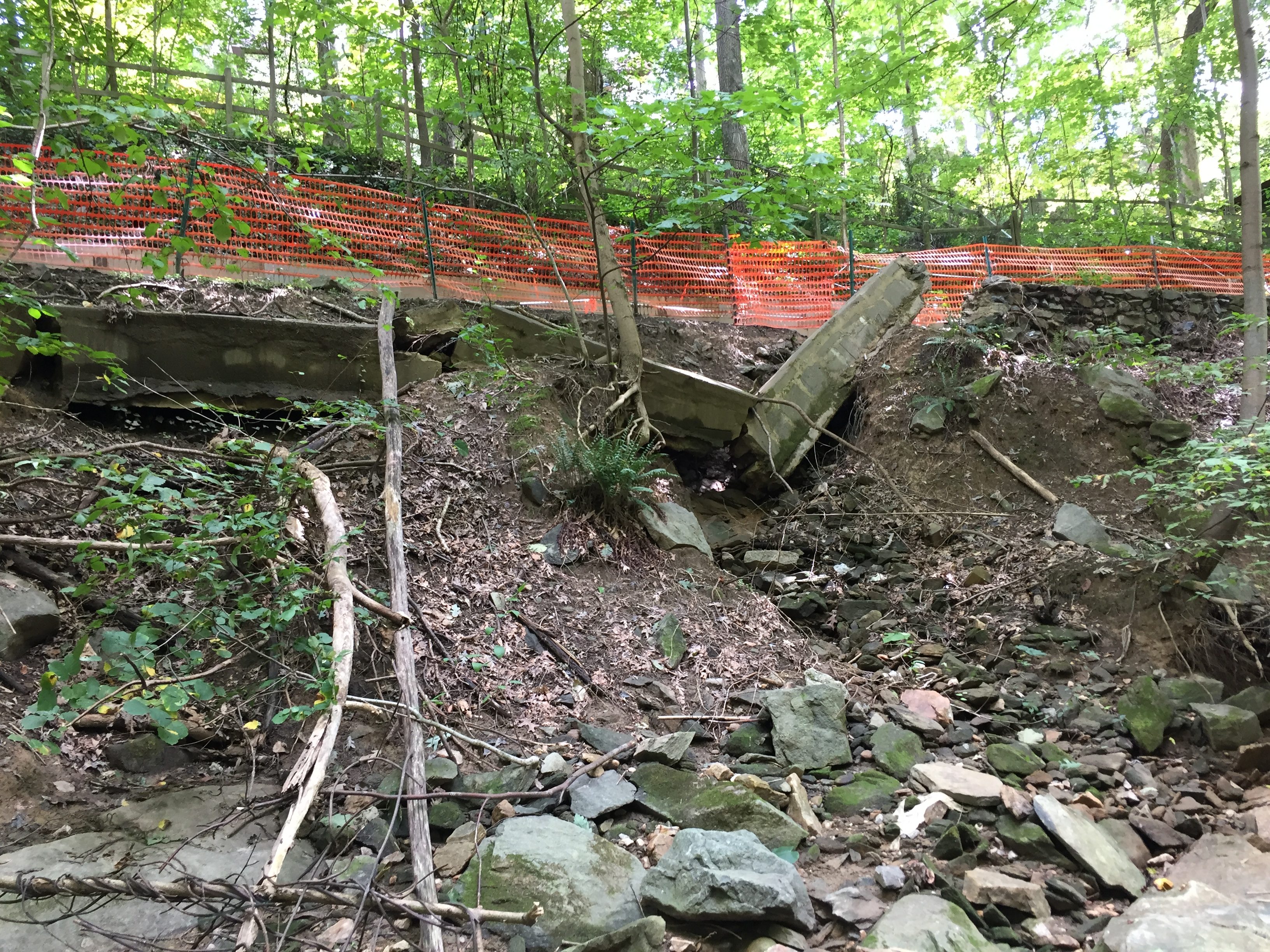 Erosion has undermined the stone wall along the trail and it has collapsed, threatening the trail.