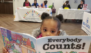 Photo with young child reading a book with title Everybody Counts!